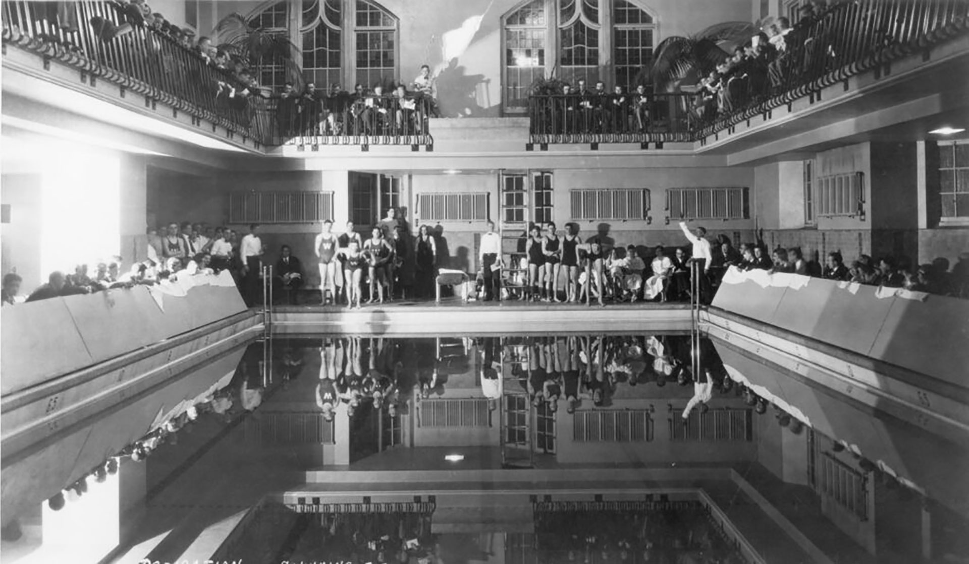 Swimmers and spectators gather around the pool for a swim meet