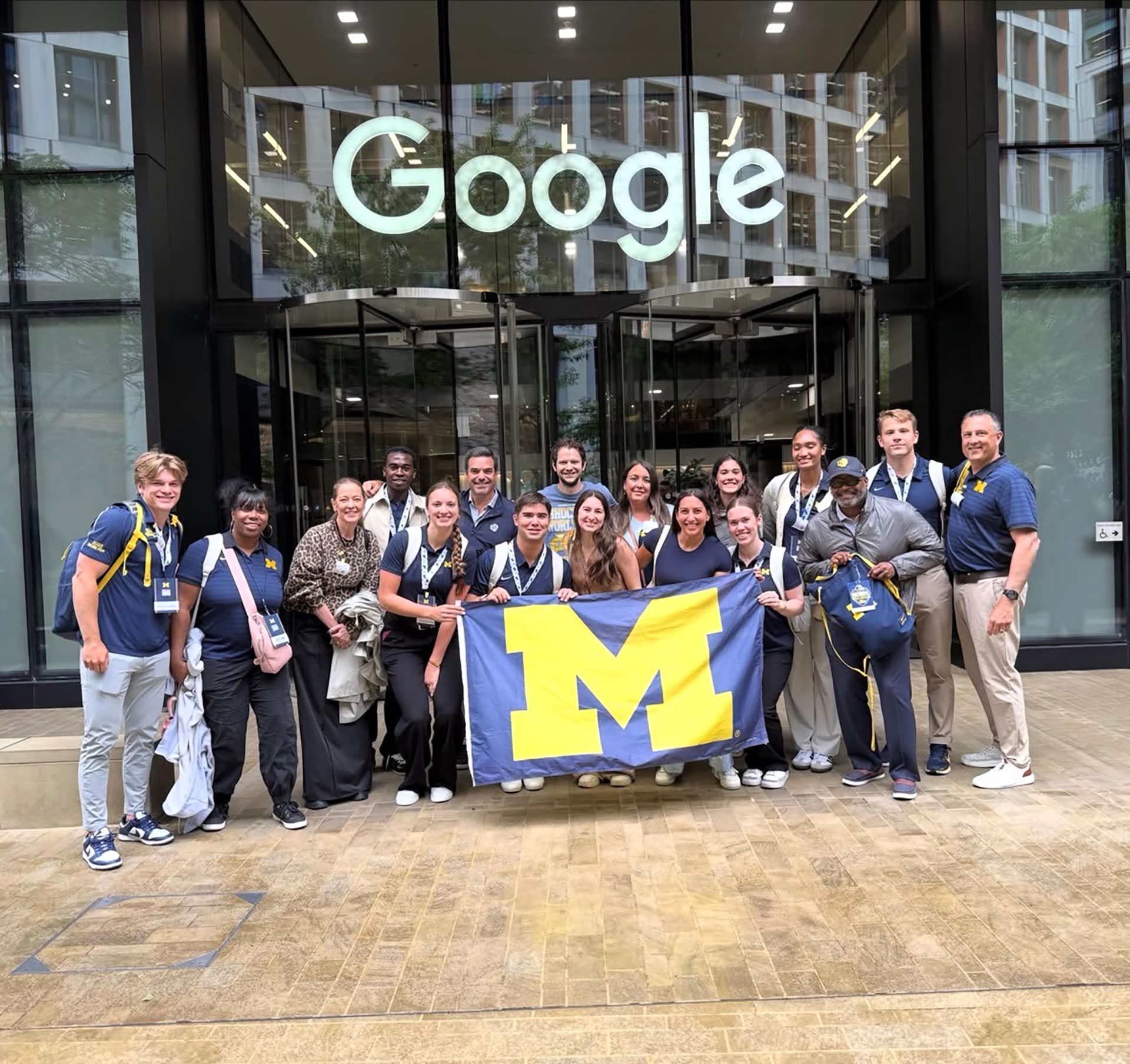 Student-athletes holding the Block M flag outside of Google's London office