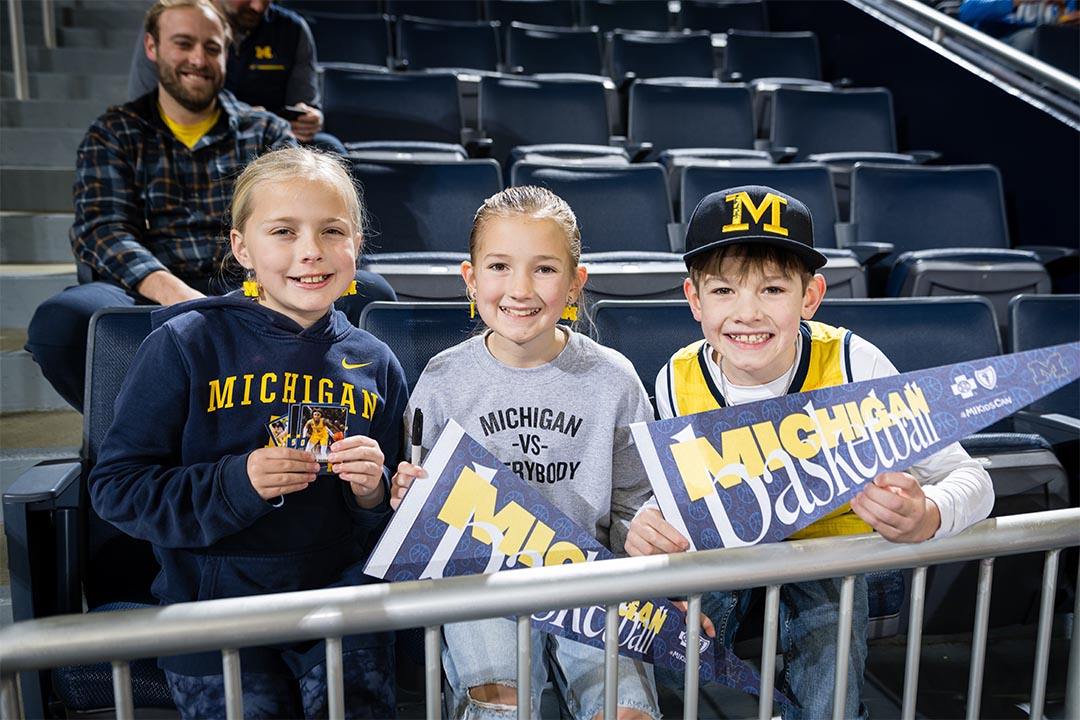 Three kids cheering at Crisler Center
